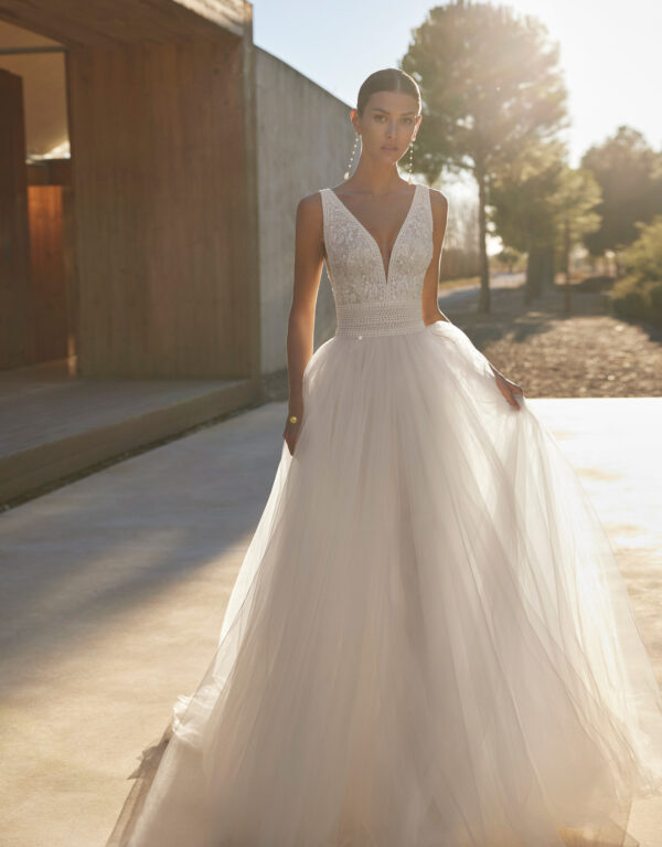 ANGEL ROSA CLARA Ρομαντικό νυφικό φόρεμα σε στυλ A-Line Princess, με μπούστο από δανδέλα σε σχήμα V. Η φούστα του από απαλό τούλι, πέφτει χυτή