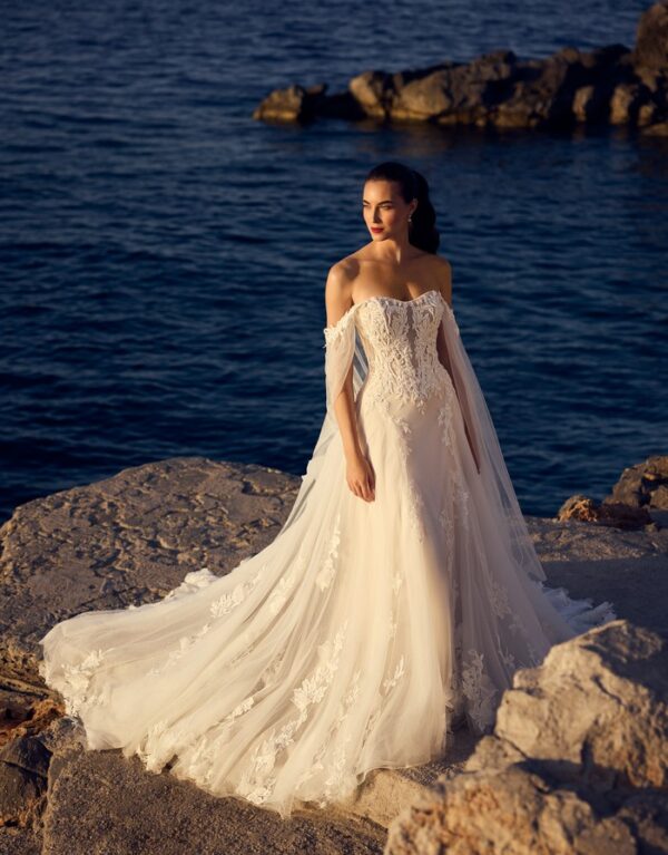 ST653 Destiny Ένα χαριτωμένο και θηλυκό νυφικό φόρεμα σε γραμμή Α, διακοσμημένο με λαμπερή floral δαντέλα και τιράντες έξω από τους ώμους, ιδανικό για τη μέρα του γάμου σας.